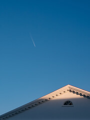 Roof gable and airplane in clear sky