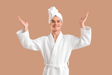 Teenage boy in bathrobe after shower on brown background