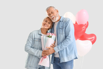 Mature couple with tulips hugging on light background. Valentine's Day celebration