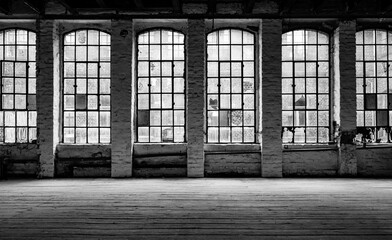Old factory windows and worn wooden floorboards in run-down factory ruins in Germany. Typical metal...