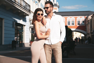 Beautiful fashion woman and her handsome elegant boyfriend. Sexy brunette model in summer clothes. Fashionable smiling couple posing in street Europe. Brutal man and female outdoors