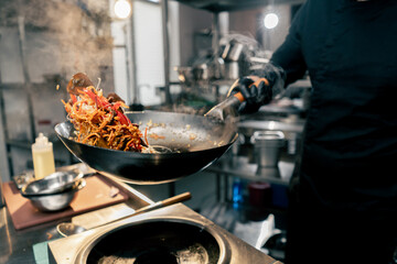 close-up of a frying pan with egg and meat over the stove with a hand in throw in the air contents