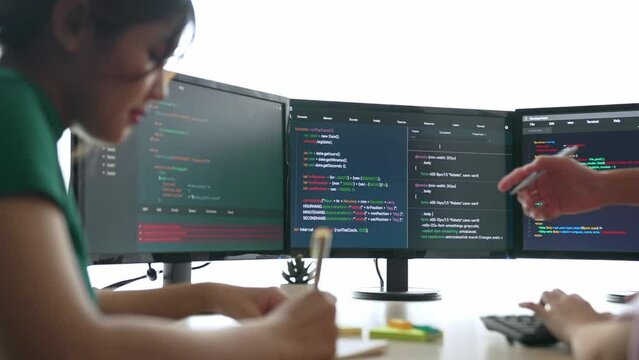 Slow motion back end software developer engineer for computer programming working together on debugging writing computing code, solving complex algorithms display on monitor in office. Burgeoning