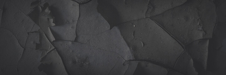 Dark wide panoramic background. Peeling paint on a concrete wall. Faded dark texture of old cracked...