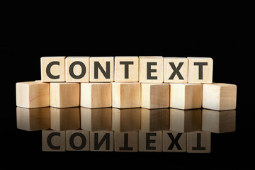 CONTEXT text assembled from wooden cubes on a black background