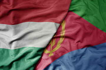 big waving national colorful flag of eritrea and national flag of hungary .