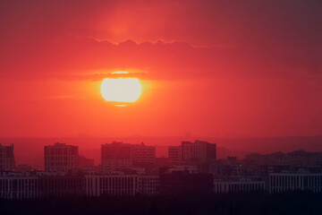 Sunset city with illumination of windows of houses. Buildings with light in residential apartments