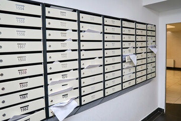 Mail boxes with overflowing documents and bills. Mailboxes with letters in the entrance of an...