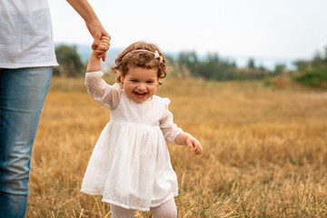Mother little child holding hands walking in a grass field.Stock photo . - 736103779