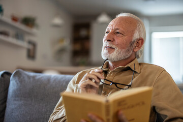 Home, relax and senior man with a book, retirement and calm with a story in a living room. Old...