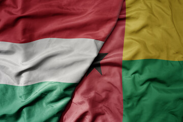 Obraz premium big waving national colorful flag of guinea bissau and national flag of hungary .