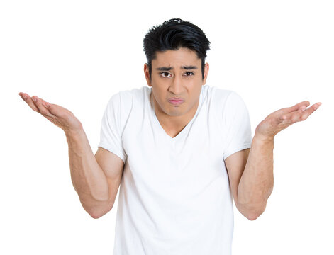 Closeup portrait of dumb clueless young man, arms out asking why what's the problem who cares so what, I don't know. Isolated on white background. 