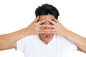 Closeup portrait of a scared, shy man covering face with hands fingers, peering through with wide eyes isolated on white background - 736107970