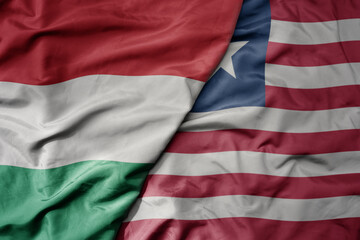 big waving national colorful flag of liberia and national flag of hungary .