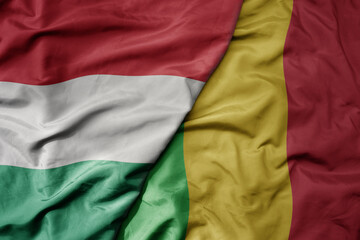 big waving national colorful flag of mali and national flag of hungary .
