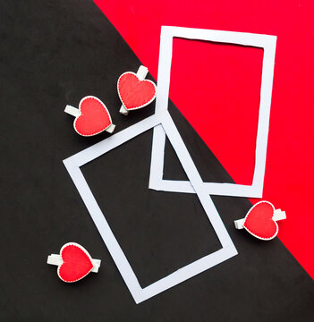 Two white mockup photo frames decorative with hearts on geometric black and red background. Minimal concept, copy space for the text. Valentine's Day greeting card