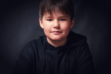 Portrait of a smiling child in a black sweater on a dark background