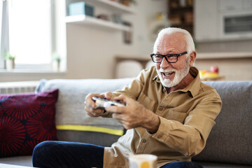 Cheerful excited gray-haired senior male gamer won video game reacts emotionally celebrate to...