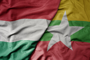 big waving national colorful flag of myanmar and national flag of hungary .