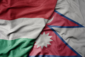 big waving national colorful flag of nepal and national flag of hungary .