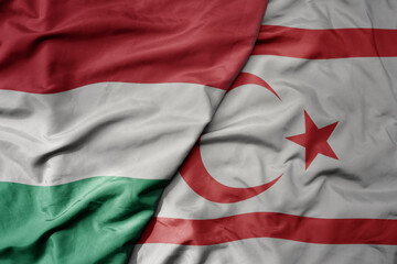 big waving national colorful flag of northern cyprus and national flag of hungary .
