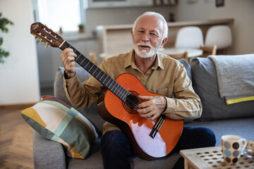 Obraz premium Shot of a senior man playing the guitar at home. Senior handsome good looking man playing guitar at home.