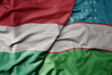 big waving national colorful flag of uzbekistan and national flag of hungary .
