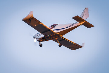 Small plane flying with sunset light in a blue sky. Light plane.