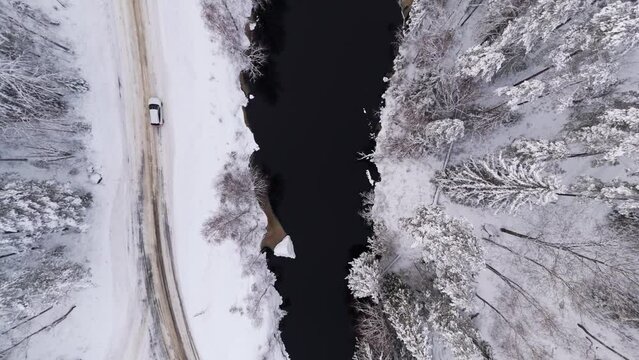 Car on winter road by river