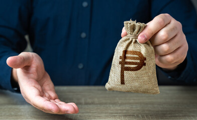 Giving gesture and philippine peso money bag. Banking and crediting. The man offers a deal in...