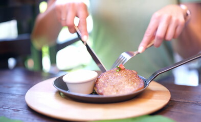 Woman eating potato pancakes with sour cream sauce from frying pan using knife and fork closeup....