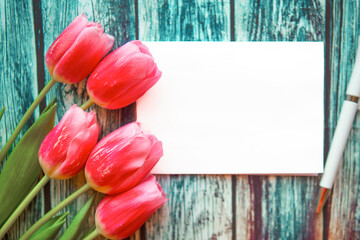 bouquet of pink tulips and mockup blank on wooden background. Easter or Mother's Day greeting card....