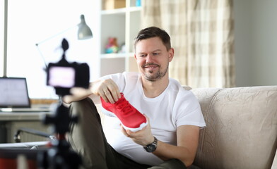 Guy front camera in apartment shows new sneakers. Video blogger demonstrates appearance product....