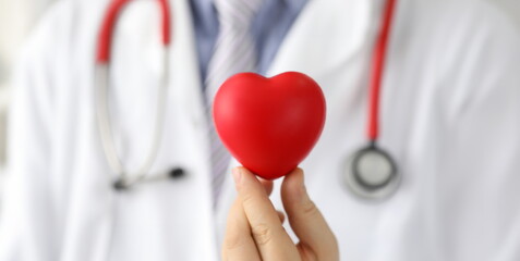 Doctor holds mock heart with black dot, pacemaker. Reduce risks heart disease. Get advice from...