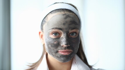 Close-up view of young beautiful woman wearing cleaning face mask. Lovely girl after bath. Skincare treatment. Wellness and beauty procedure at home concept