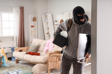 Male thief stealing safe and monitor in room