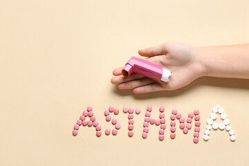 Child's hand with inhaler and word ASTHMA made of pills on beige background