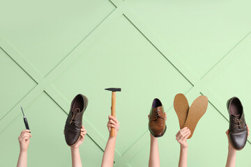 Female hands with shoes, insoles and craft tools on green wooden background. Shoe repair concept