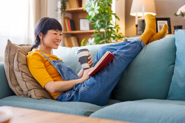 Woman drinking coffee and reading a book at home