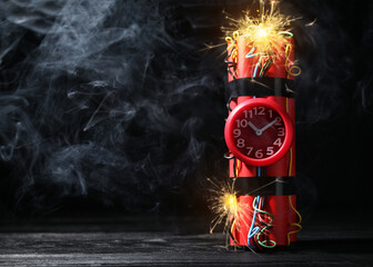 Dynamite time bomb with burning wires on black wooden table, space for text - obrazy, fototapety, plakaty