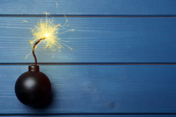 Old fashioned black bomb with lit fuse on blue wooden table, top view. Space for text - obrazy, fototapety, plakaty