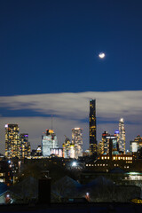 Naklejka premium Moonrise over New York City Skyline, a tranquil nostalgic twilight landscape over Brooklyn rooftops on a cloudy winter night, USA