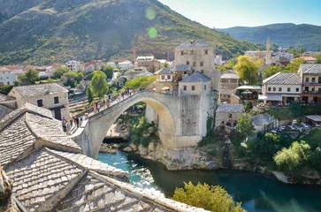 Photo sur Plexiglas Stari Most View of the Old Bridge in Mostar city in Bosnia and Herzegovina during a sunny day. Neretva river. Unesco World Heritage Site. People walking over the bridge.