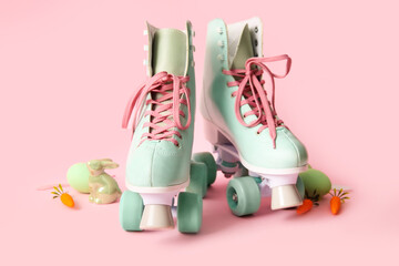 Vintage roller skates with Easter eggs, carrots and toy bunny on pink background