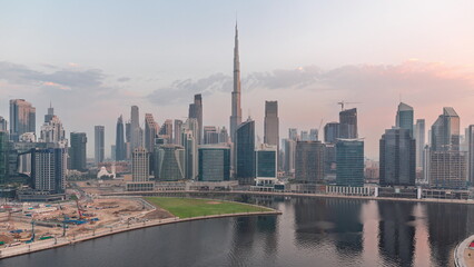 Fototapeta premium Aerial view to Dubai Business Bay and Downtown with the various skyscrapers and towers night to day timelapse