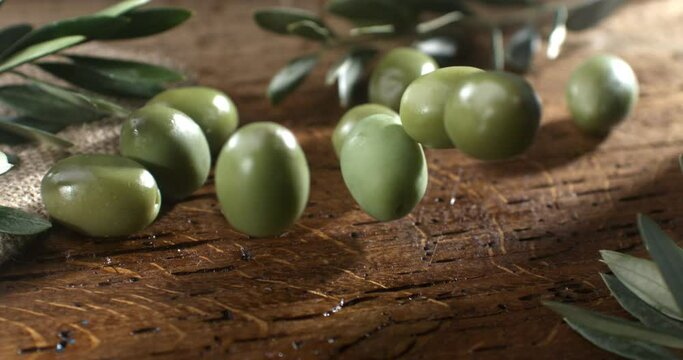 Super slow motion macro of fresh bio organic olive golden oil are falling on wooden rustic table in kitchen of restaurant at 1000 fps.