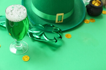Glass of beer with coins, decorative glasses and leprechaun hat on green background. St. Patrick's...