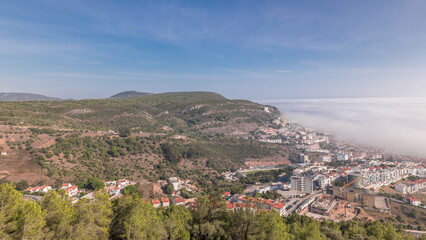 Fototapeta na wymiar Panorama showing aerial View of Sesimbra Town and Port covered by fog timelapse, Portugal.