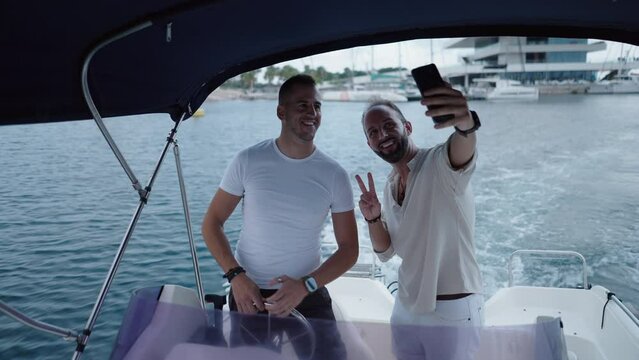 A couple of caucasian adult men taking a selfie in a boat