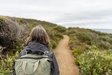 Mother with baby in a carrier on her chest on a hike, taking a bush walk in Summer in a national park